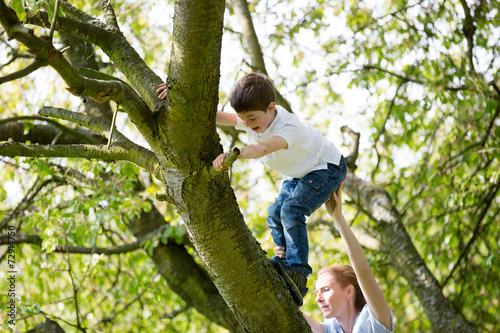 Mutter hilft Kind beim klettern auf dem Baum
