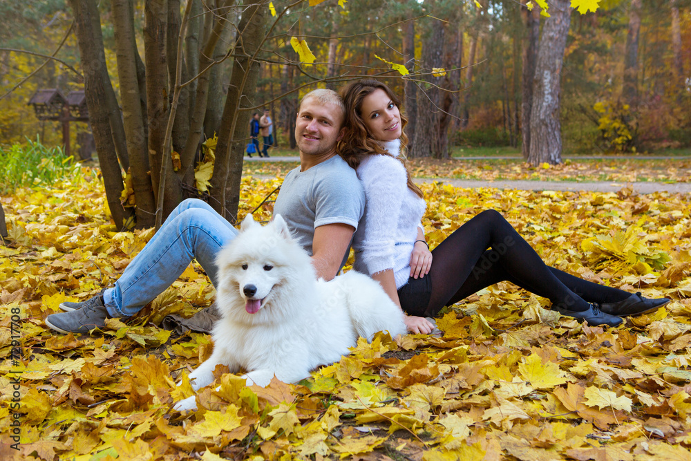 Young couple with a dog in the autumn forest Young couple with a dog in the autumn forest