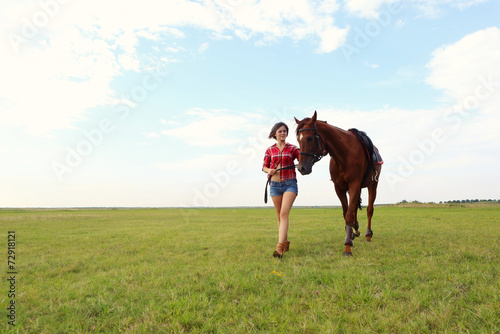 Portrait of young woman with her horse on the meadow
