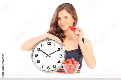 Beautiful woman holding a strawberry and a clock photo