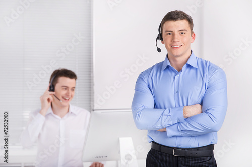 two young call center men talking by phone.