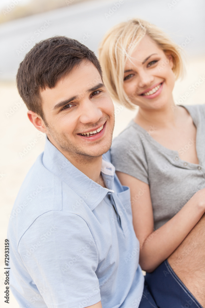 Attractive young couple sitting on beach at summer Attractive young couple sitting on beach at summer