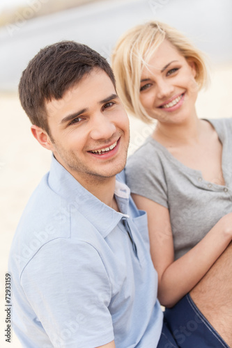Attractive young couple sitting on beach at summer