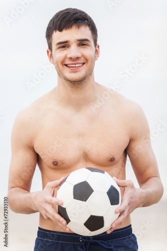 Close-up of male playing football on sand.