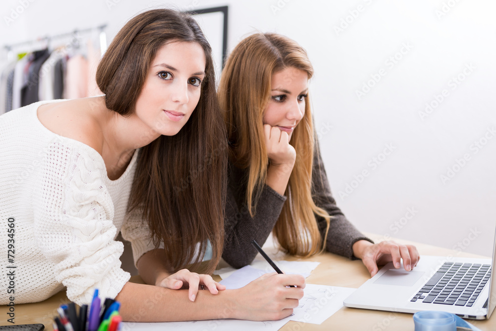Young attractive females fashion designers leaning on office des Young attractive females fashion designers leaning on office des