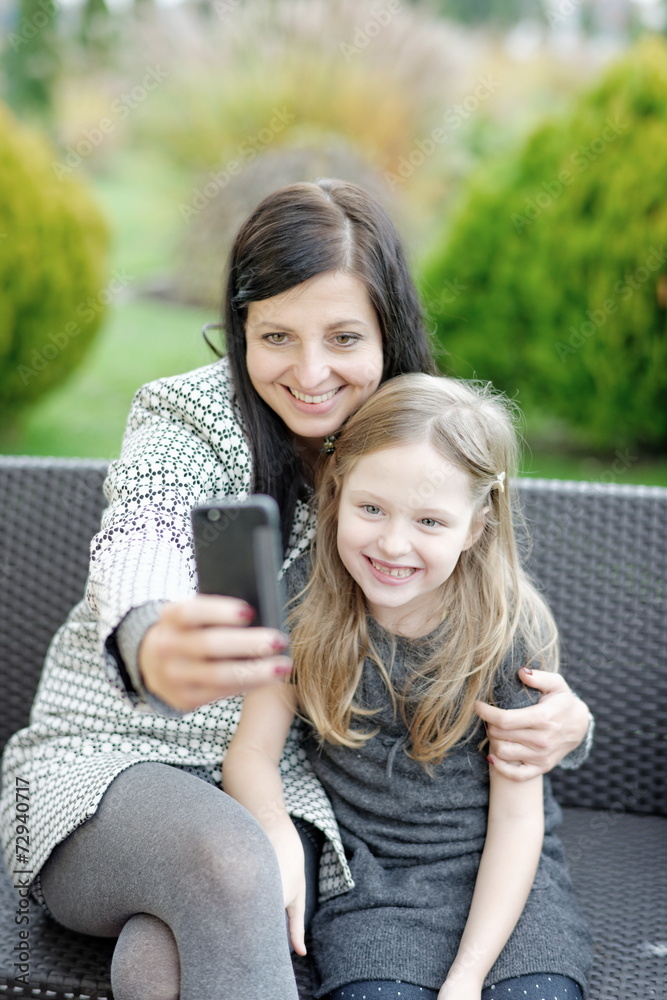 Mother and daughter sitting in nature and talking selfie with Mother and daughter sitting in nature and talking selfie with