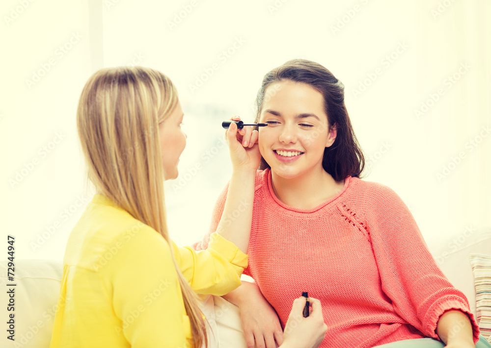 two smiling teenage girls applying make up at home two smiling teenage girls applying make up at home