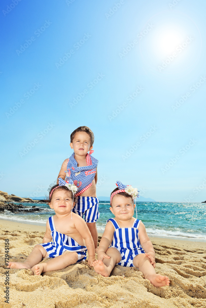 Three cute babies posing on a beach Three cute babies posing on a beach