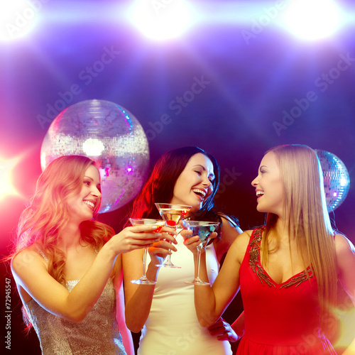 three smiling women with cocktails and disco ball