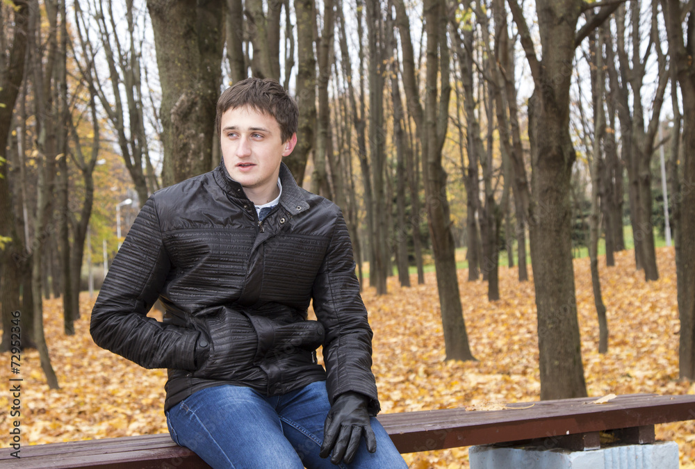A man sits on a bench in autumn park A man sits on a bench in autumn park