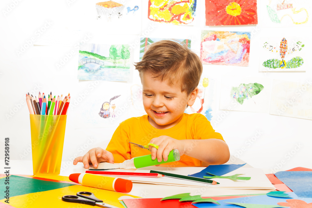 Happy small boy crafts with scissors, paper, glue Happy small boy crafts with scissors, paper, glue