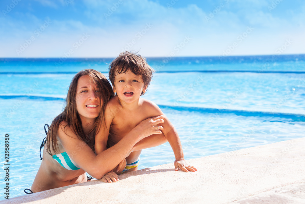 Mother and her kid hugging with sea on background