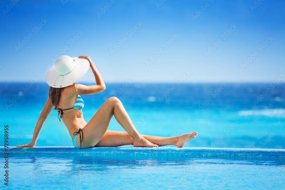 Girl from back with white hat in striped bikini