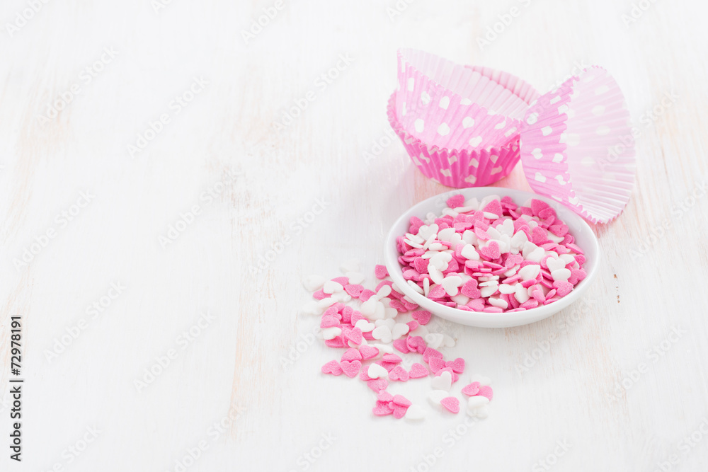 colored sugar hearts and paper baking dishes on white wood colored sugar hearts and paper baking dishes on white wood