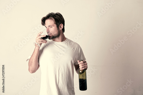 Young man relaxing with a bottle of red win photo