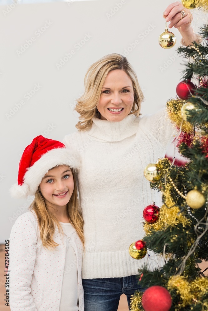 Festive mother and daughter decorating christmas tree Festive mother and daughter decorating christmas tree
