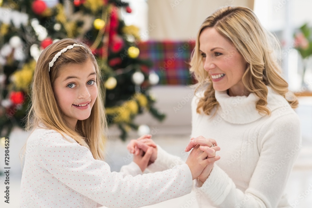 Festive mother and daughter beside christmas tree Festive mother and daughter beside christmas tree