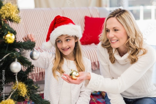 Festive mother and daughter decorating christmas tree