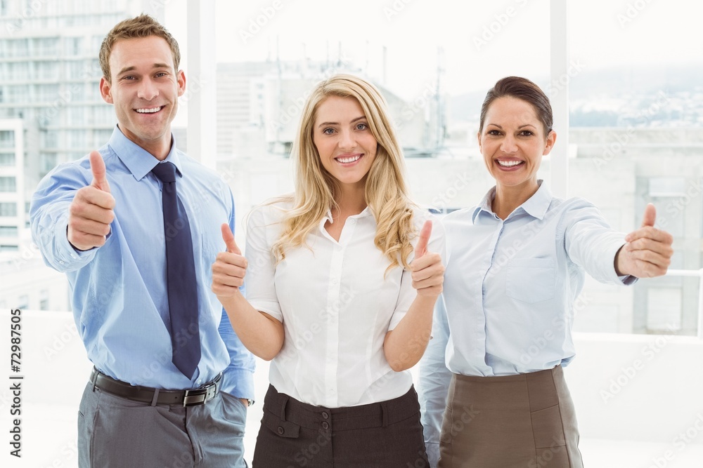 Business people gesturing thumbs up in office Business people gesturing thumbs up in office
