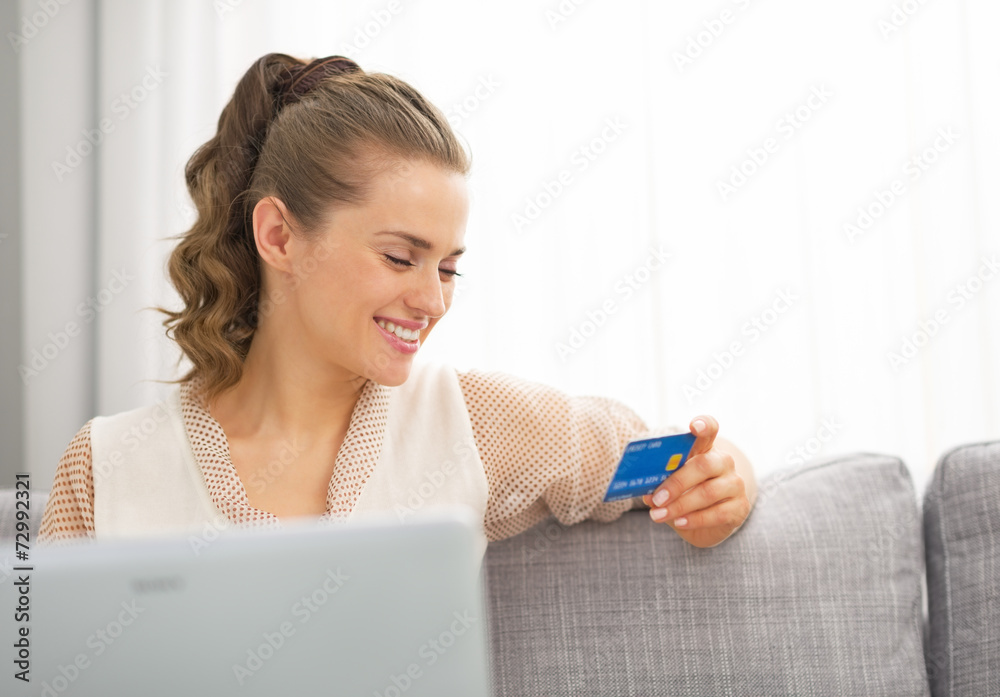 Happy young housewife looking on credit card Happy young housewife looking on credit card