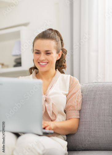 Happy young housewife using laptop in living room Free Download Happy young housewife using laptop in living room - GFXLoad