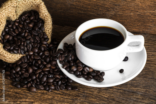 cup of coffee with coffee seed on wooden background