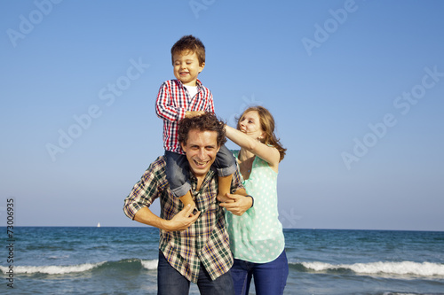 Obraz na płótnie Niño riéndose y disfrutando con sus padres en la playa w salonie