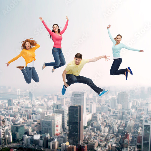 group of smiling teenagers jumping in air