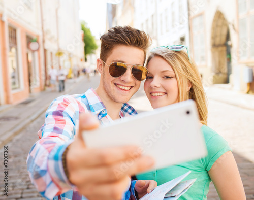 smiling couple with smartphone in city