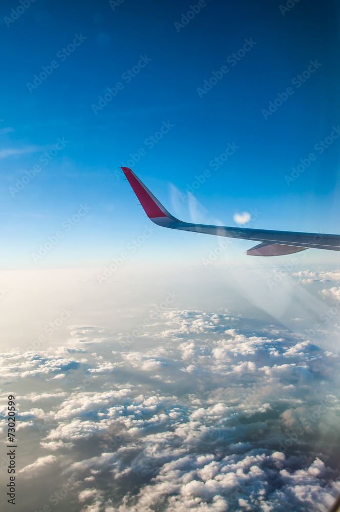 Fototapeta premium Wing of an airplane flying above the clouds