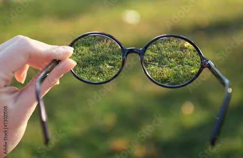 Vision concept. Glasses in hand on green background