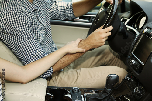 Loving couple holding hands in car close-up