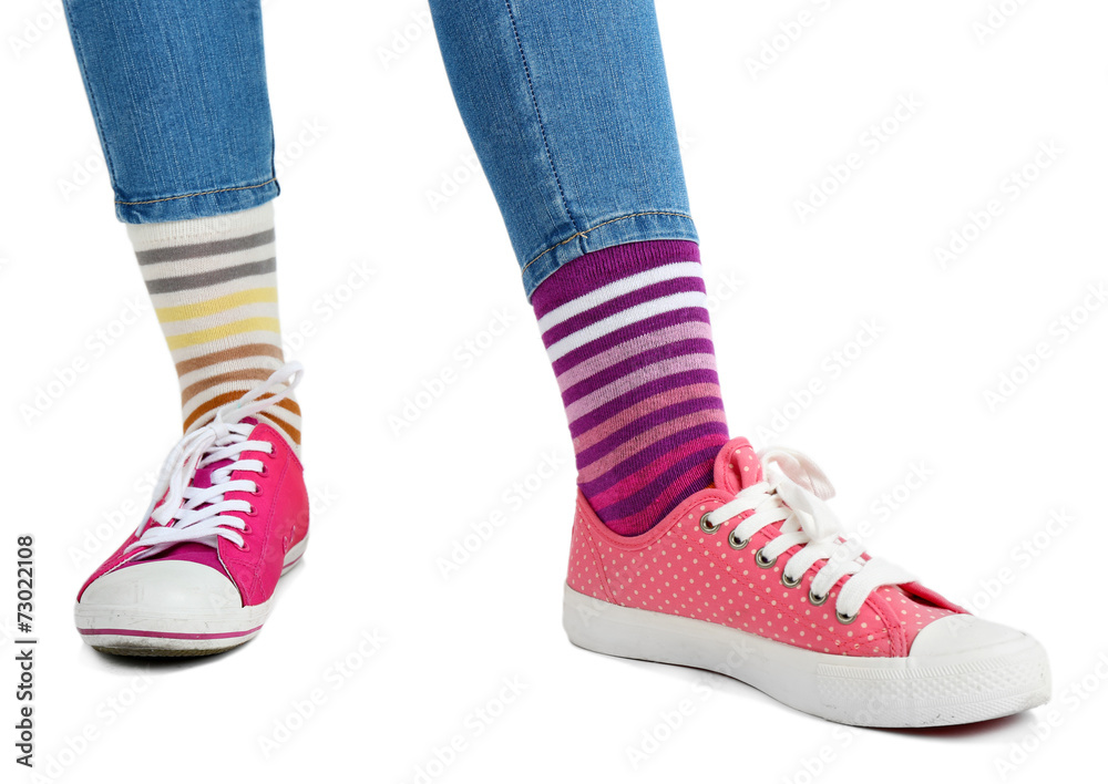 Female legs in colorful socks and sneakers isolated on white