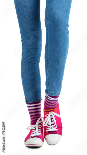 Female legs in colorful socks and sneakers isolated on white