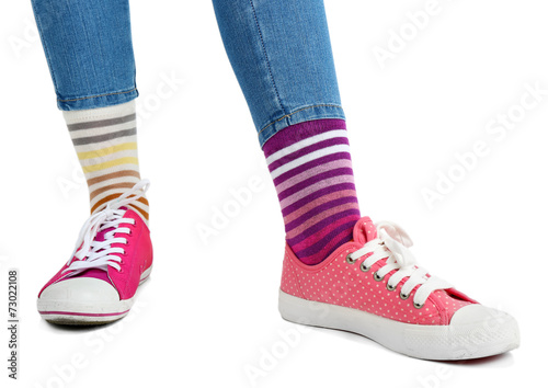 Female legs in colorful socks and sneakers isolated on white