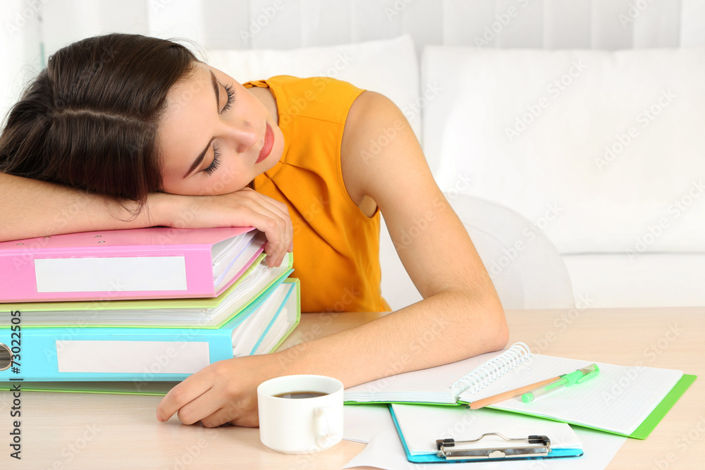 Tired girl with many folders sleeps on table Tired girl with many folders sleeps on table