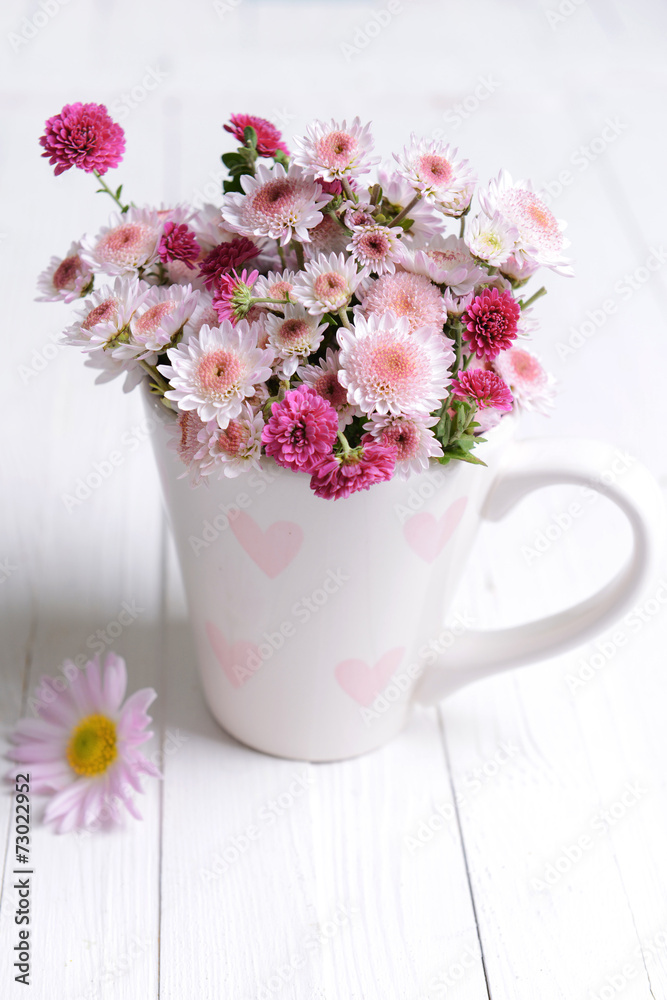 Beautiful flowers in cup on table close-up Beautiful flowers in cup on table close-up