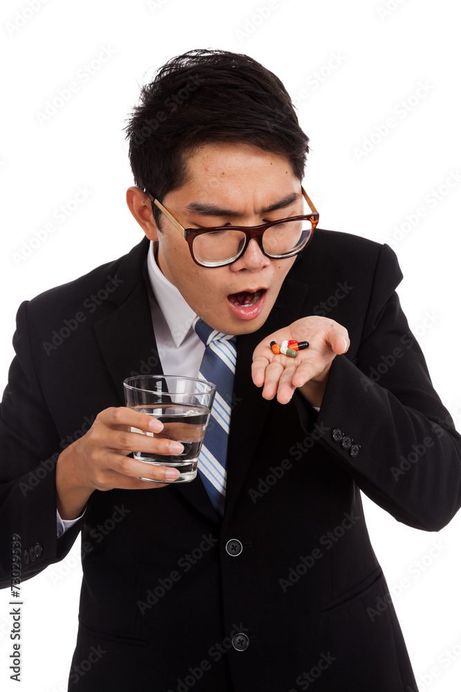 Asian businessman about to eat medicine with glass of water Asian businessman about to eat medicine with glass of water
