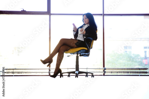 Business woman sitting in the chair with smartphone