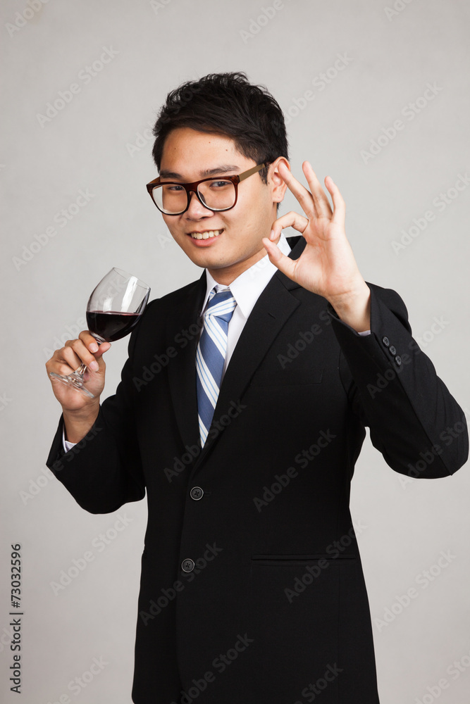 Asian businessman show OK with glass of red wine Asian businessman show OK with glass of red wine