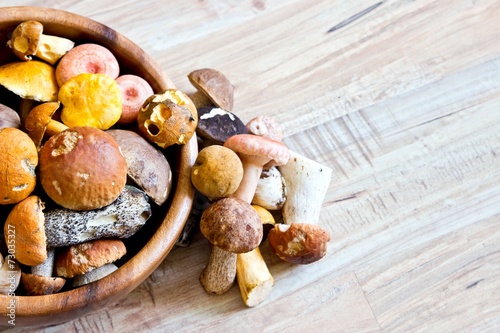 Mixed forest mushrooms in wooden bowl close up