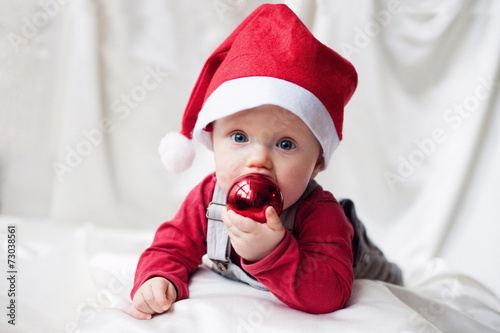 Funny baby in Santa Claus cap with a Christmas ball