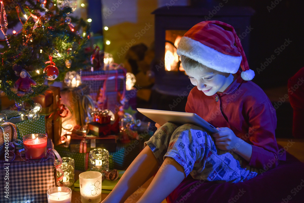 Christmastime, a little boy with a hat of Santa Claus plays on a Christmastime, a little boy with a hat of Santa Claus plays on a