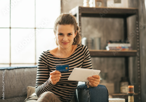 Portrait of happy young woman with credit card and tablet pc