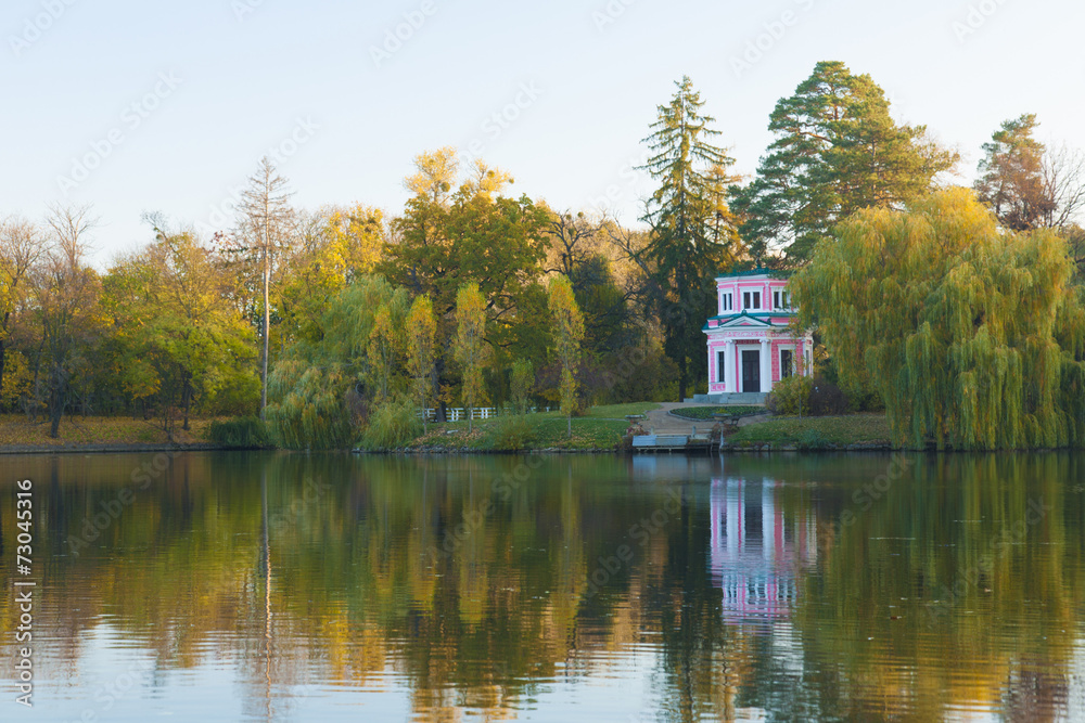 Ancient pink pavilion on autumn park lake