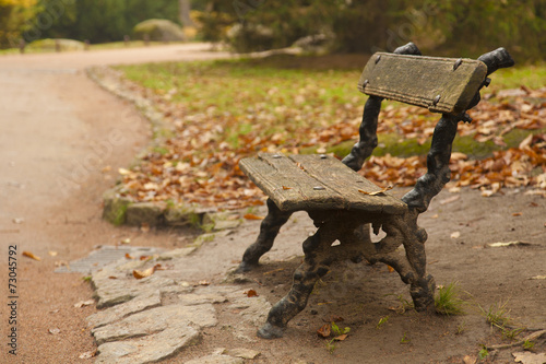Lonely bench by a road in autumn park