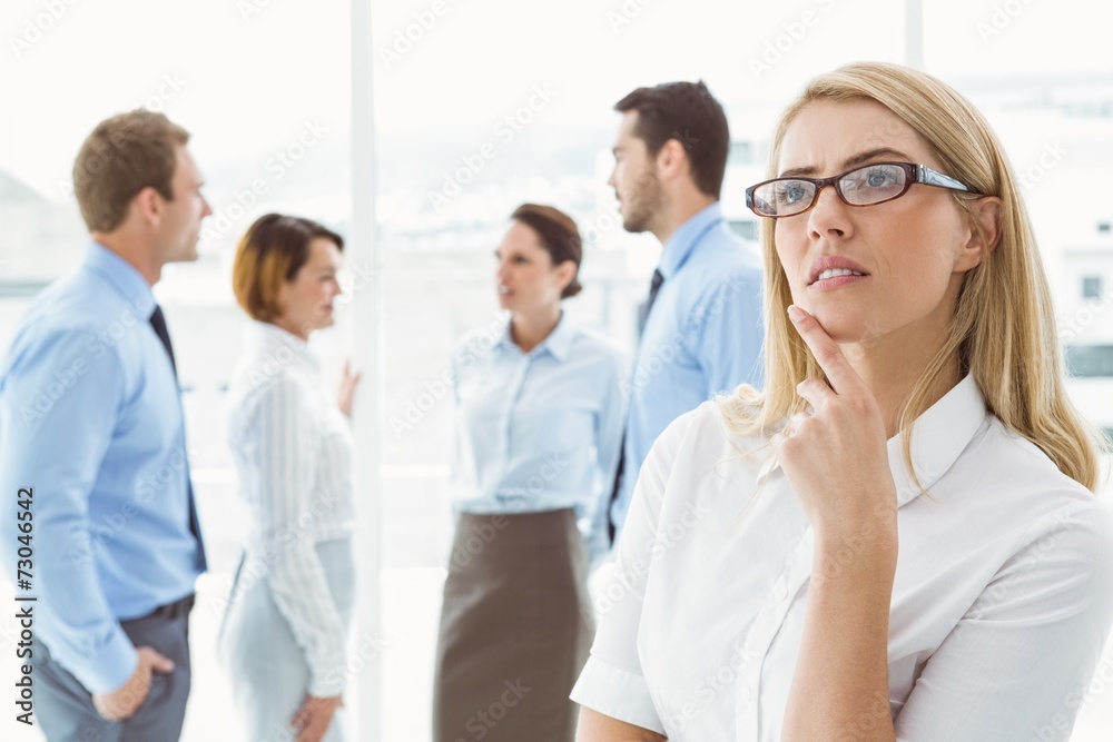 Thoughtful businesswoman with colleagues behind Thoughtful businesswoman with colleagues behind