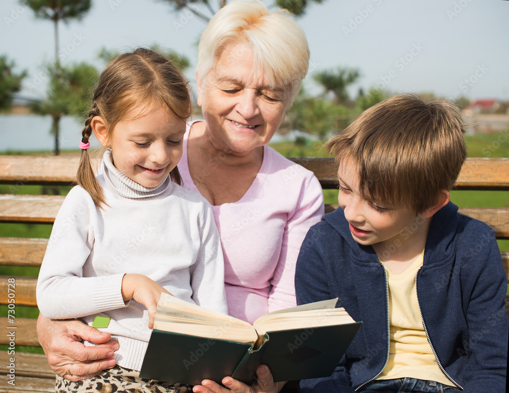 grgrandmother reading book to grandchildren outdoors grgrandmother reading book to grandchildren outdoors