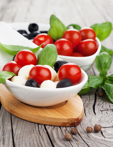 Fresh cherry tomatoes  mozzarella  olive and basil on old wooden