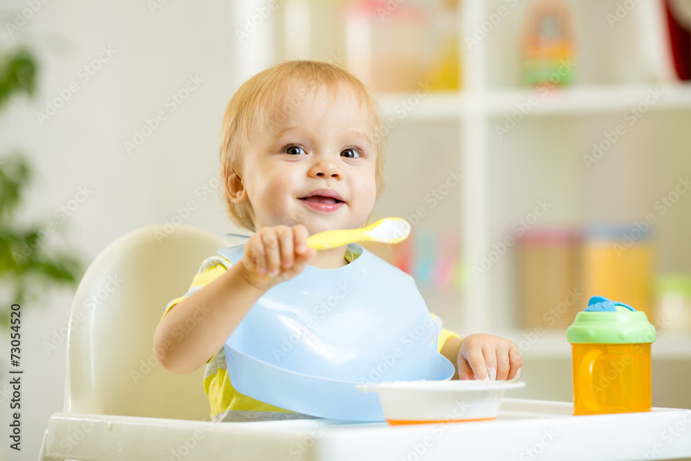 funny baby child boy eating itself with spoon in kitchen funny baby child boy eating itself with spoon in kitchen